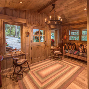 Inredning av en eklektisk stor foajé, med bruna väggar, mellanmörkt trägolv, en tvådelad stalldörr, mellanmörk trädörr och brunt golv