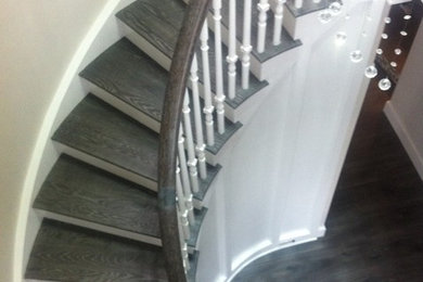 Foto de escalera curva clásica grande con escalones de madera, contrahuellas de madera pintada y barandilla de madera