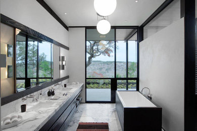 Design ideas for a mid-sized contemporary master bathroom in Austin with flat-panel cabinets, dark wood cabinets, a freestanding tub, white tile, stone slab, white walls, marble floors, an undermount sink and marble benchtops.
