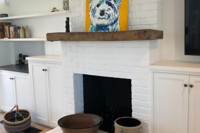 Inspiration for a coastal medium tone wood floor family room remodel in San Luis Obispo with a standard fireplace and a brick fireplace