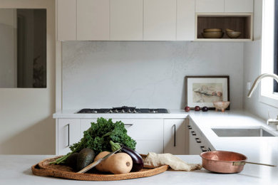 Design ideas for a mid-sized modern u-shaped eat-in kitchen in Melbourne with a single-bowl sink, flat-panel cabinets, beige cabinets, quartz benchtops, white splashback, engineered quartz splashback, stainless steel appliances, light hardwood floors, a peninsula, yellow floor and white benchtop.