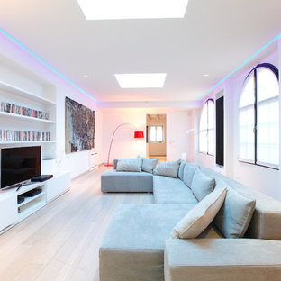 Modern inredning av ett stort allrum med öppen planlösning, med vita väggar, ljust trägolv och en fristående TV