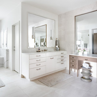 Transitional master white tile and limestone tile porcelain floor and beige floor drop-in bathtub photo in Dallas with a one-piece toilet, white walls, white countertops, flat-panel cabinets, white cabinets and an undermount sink