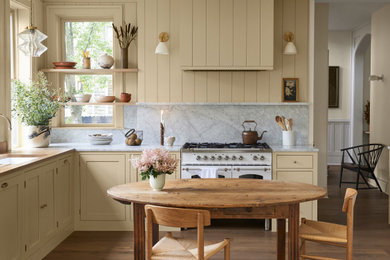 Design ideas for a medium sized classic kitchen/diner in Columbus with shaker cabinets, yellow cabinets, marble worktops, grey splashback, marble splashback, white appliances, medium hardwood flooring, no island, brown floors and grey worktops.