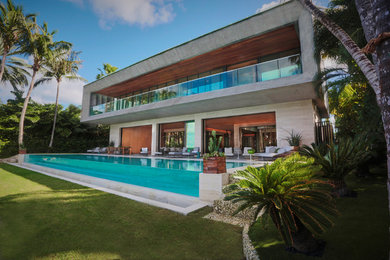 Large contemporary backyard rectangular infinity pool in Miami with natural stone pavers.