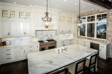 Eat-in kitchen - large contemporary u-shaped dark wood floor eat-in kitchen idea in Vancouver with an undermount sink, raised-panel cabinets, white cabinets, marble countertops, white backsplash, stone slab backsplash, stainless steel appliances and an island