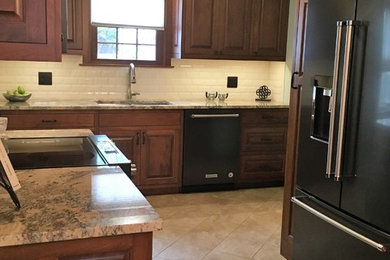 Inspiration for a small transitional porcelain tile and beige floor kitchen remodel in New York with an undermount sink, raised-panel cabinets, medium tone wood cabinets, granite countertops, subway tile backsplash and stainless steel appliances