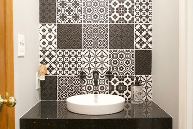 Example of a small trendy black and white tile and porcelain tile vinyl floor and black floor powder room design in Toronto with a two-piece toilet, gray walls, a vessel sink, quartz countertops and black countertops