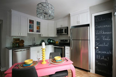 Mid-sized trendy l-shaped light wood floor and yellow floor enclosed kitchen photo in Montreal with an undermount sink, shaker cabinets, white cabinets, granite countertops, white backsplash, porcelain backsplash, stainless steel appliances and gray countertops