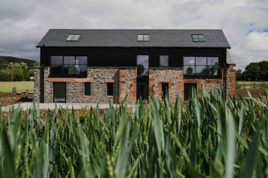 Mid-sized trendy black two-story stone exterior home photo in Edinburgh with a tile roof and a gray roof