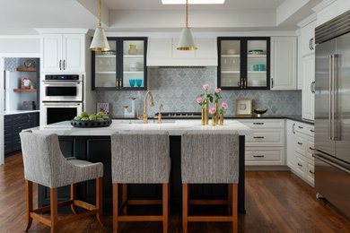 Inspiration for a transitional l-shaped medium tone wood floor, brown floor and tray ceiling eat-in kitchen remodel in Dallas with gray backsplash, stainless steel appliances, an island and multicolored countertops