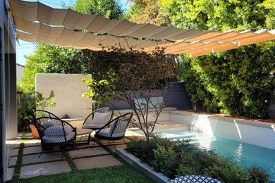 Example of a small minimalist backyard concrete paver patio design in Los Angeles with a fire pit and a pergola