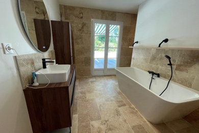 Exemple d'une grande salle de bain méditerranéenne avec une baignoire posée, un carrelage beige et du carrelage en travertin.
