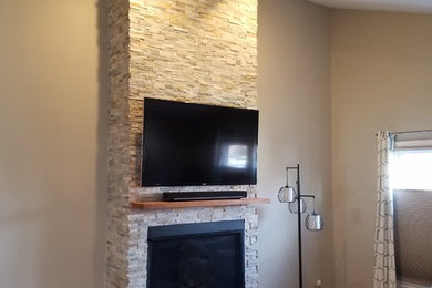 Large transitional open concept light wood floor and brown floor living room photo in Chicago with beige walls, a standard fireplace, a stone fireplace and a wall-mounted tv