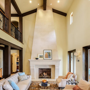 Ejemplo de salón para visitas tipo loft, mediterráneo, de tamaño medio, sin televisor, con paredes amarillas, chimenea tradicional, marco de chimenea de piedra y suelo beige