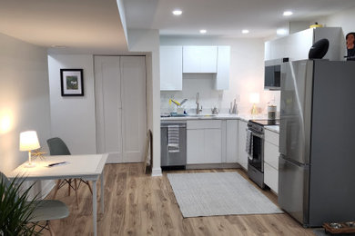 Foto de cocina actual abierta con fregadero bajoencimera, armarios con paneles lisos, puertas de armario blancas, encimera de cuarcita y suelo vinílico