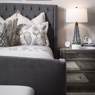 Modern inredning av ett stort huvudsovrum, med grå väggar, mellanmörkt trägolv och en bred öppen spis