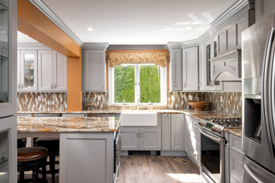 ニューヨークにある高級な広いトランジショナルスタイルのおしゃれなキッチン (落し込みパネル扉のキャビネット、グレーのキャビネット、御影石カウンター、黄色いキッチンカウンター、エプロンフロントシンク、黄色いキッチンパネル、ガラスタイルのキッチンパネル、シルバーの調理設備、ラミネートの床、茶色い床) の写真