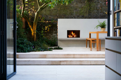 Small contemporary backyard partial sun garden in London with with fireplace and decking.