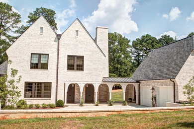 This is an example of an expansive transitional two-storey brick house exterior in Charlotte with a clipped gable roof and a shingle roof.