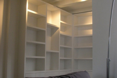Diseño de biblioteca en casa abierta actual de tamaño medio con paredes blancas y suelo de madera en tonos medios