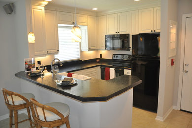 Cette photo montre une cuisine américaine avec un évier 2 bacs, des portes de placard blanches et un électroménager noir.