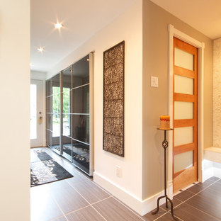 モントリオールの中サイズの片開きドアコンテンポラリースタイルのおしゃれな玄関ホール (グレーの壁、磁器タイルの床、白いドア、グレーの床) の写真