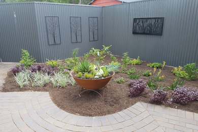 Photo of a mid-sized country backyard partial sun xeriscape for fall in Adelaide with a garden path and concrete pavers.