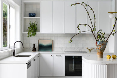 Design ideas for a contemporary kitchen in Sydney with an undermount sink, shaker cabinets, white cabinets, quartz benchtops, white splashback, terra-cotta splashback, black appliances, porcelain floors, with island, grey floor and grey benchtop.