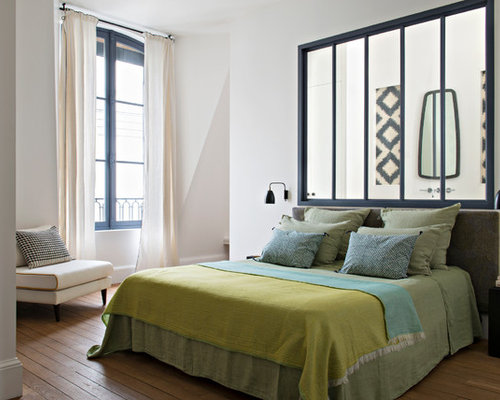 Inspiration pour une chambre adulte design avec un mur blanc, un sol en bois brun et un sol marron.