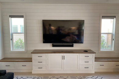 Imagen de salón de estilo de casa de campo con paredes blancas, televisor colgado en la pared y machihembrado