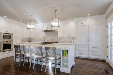 Inspiration for a large transitional l-shaped medium tone wood floor and brown floor open concept kitchen remodel in St Louis with an undermount sink, recessed-panel cabinets, white cabinets, marble countertops, white backsplash, subway tile backsplash, paneled appliances, an island and white countertops