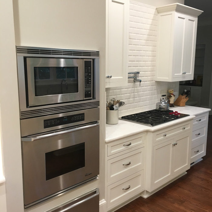 The cooktop ended up being located in a place where we needed a downdraft, which created an opening for the rear wall.  This is a very clean look, and functions fine for the cooktop the clients use.