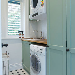 Imagen de lavadero multiusos y lineal, de estilo de casa de campo, grande, con armarios con paneles empotrados, paredes blancas, fregadero encastrado, encimera de madera, suelo de mármol, lavadora y secadora apiladas, puertas de armario turquesas y encimeras beige