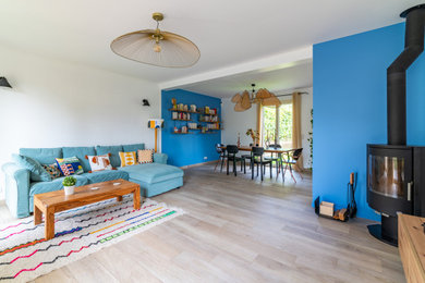 Idée de décoration pour un grand salon ouvert avec un mur bleu, sol en stratifié, une cheminée d'angle, un téléviseur indépendant et un sol beige.