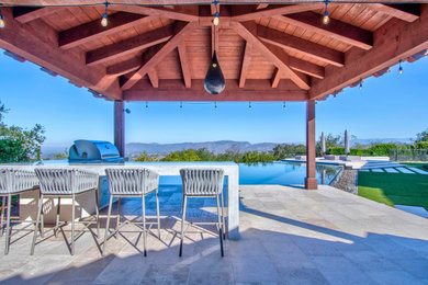 Pool house - large modern backyard stone and rectangular infinity pool house idea in San Diego
