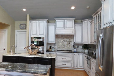 Transitional u-shaped separate kitchen in Charlotte with a drop-in sink, distressed cabinets, white splashback, stainless steel appliances, medium hardwood floors and multiple islands.