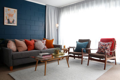 Small eclectic open concept living room in Auckland with blue walls and carpet.