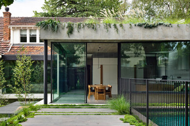 Large one-storey concrete grey house exterior in Melbourne with a flat roof and a green roof.