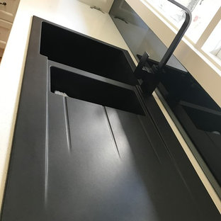 Bild på ett mellanstort lantligt kök, med en dubbel diskho, luckor med infälld panel, vita skåp, bänkskiva i kvarts, glaspanel som stänkskydd, rostfria vitvaror, korkgolv och en köksö