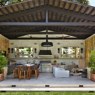 Mediterranean patio in Chicago with an outdoor kitchen, natural stone pavers and a roof extension.