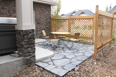Photo of a mid-sized front yard stone landscaping in Calgary with a fire pit.