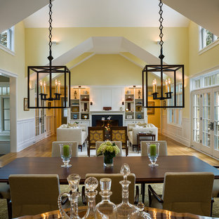 Large traditional open plan dining in Philadelphia with yellow walls, medium hardwood floors, a standard fireplace, a wood fireplace surround and brown floor.