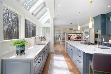Inspiration for a large transitional u-shaped medium tone wood floor and brown floor eat-in kitchen remodel in Chicago with an undermount sink, recessed-panel cabinets, blue cabinets, quartz countertops, white backsplash, stone slab backsplash, stainless steel appliances, an island and white countertops