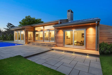 Example of a large minimalist brown one-story wood exterior home design in Newark with a clipped gable roof