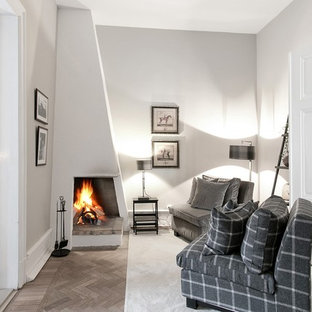 Esempio di un piccolo soggiorno vittoriano chiuso con pareti bianche, camino ad angolo, cornice del camino in intonaco, parquet chiaro, nessuna TV e pavimento beige