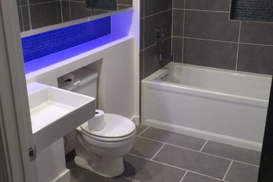 Inspiration for a mid-sized contemporary 3/4 gray tile and porcelain tile porcelain tile bathroom remodel in Cleveland with a two-piece toilet, white walls and a wall-mount sink