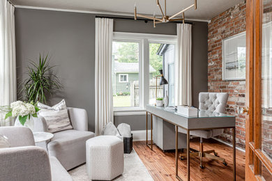 Example of a small transitional freestanding desk medium tone wood floor, brown floor, wallpaper ceiling and brick wall study room design in Toronto with gray walls and no fireplace