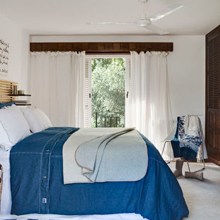 This is an example of a mid-sized beach style master bedroom in Other with white walls, terra-cotta floors and no fireplace.