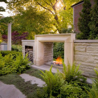 This is an example of a transitional backyard shaded garden in Toronto with with fireplace.
